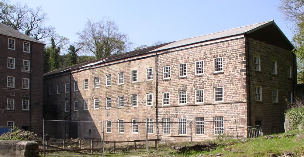 Le bâtiment d'origine de la filature de Cromford (1771), une haute usine en pierre de plusieurs étages dans la vallée de la Derwent, dans le Derbyshire.