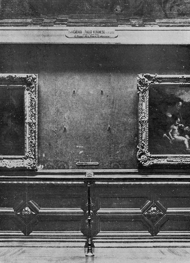 Old black-and-white photo of a museum wall with four bare iron pegs where a painting should hang, between other framed paintings.