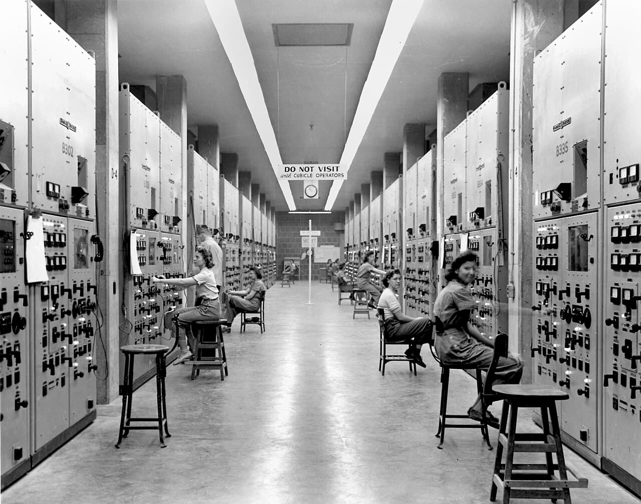 Rows of young women operating calutron control panels at the Y-12 plant in Oak Ridge, Tennessee, during World War II.