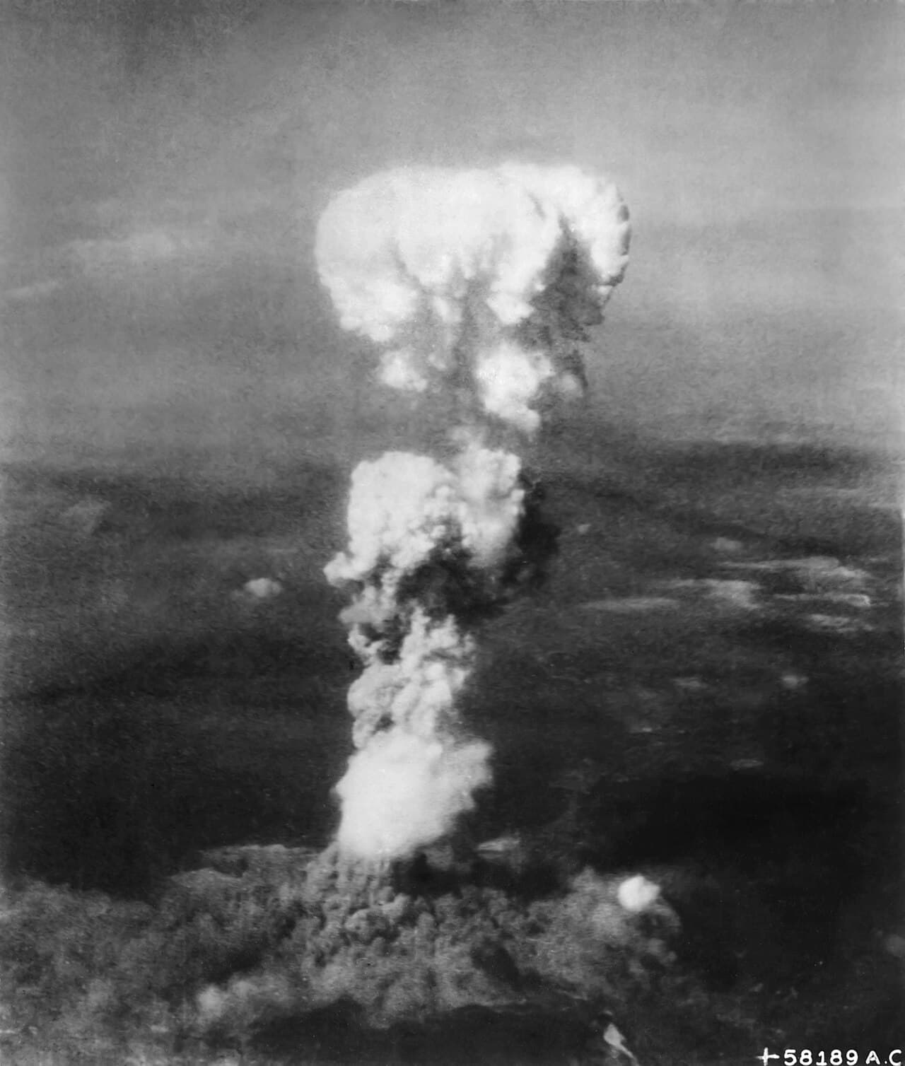 Photo en noir et blanc d'un immense champignon atomique s'élevant au-dessus d'Hiroshima après le bombardement.