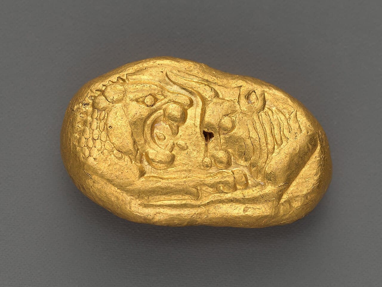 A small gold coin showing the foreparts of a lion and a bull facing each other.