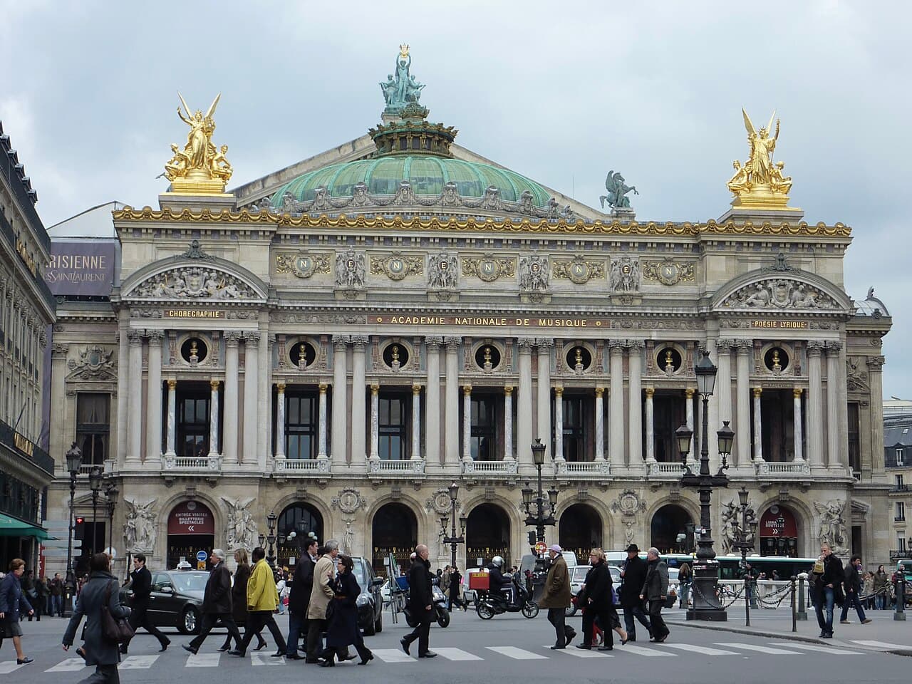 La façade ornée du Palais Garnier à Paris, décorée de colonnes, de statues et de marbre multicolore.