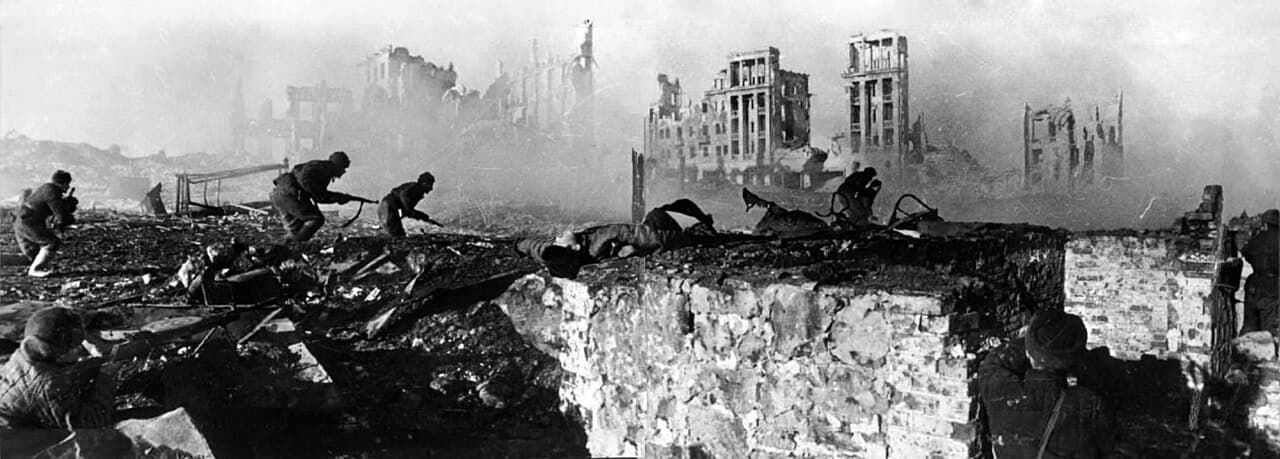 Photo en noir et blanc de soldats soviétiques avançant parmi les ruines bombardées d'un bâtiment à Stalingrad.