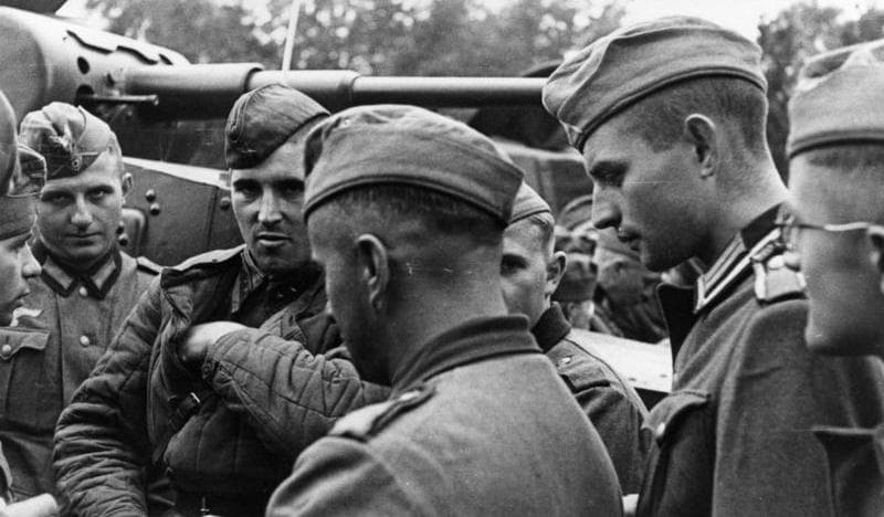 Photo en noir et blanc de soldats allemands et soviétiques se tenant ensemble et discutant après l'invasion conjointe de la Pologne en 1939.