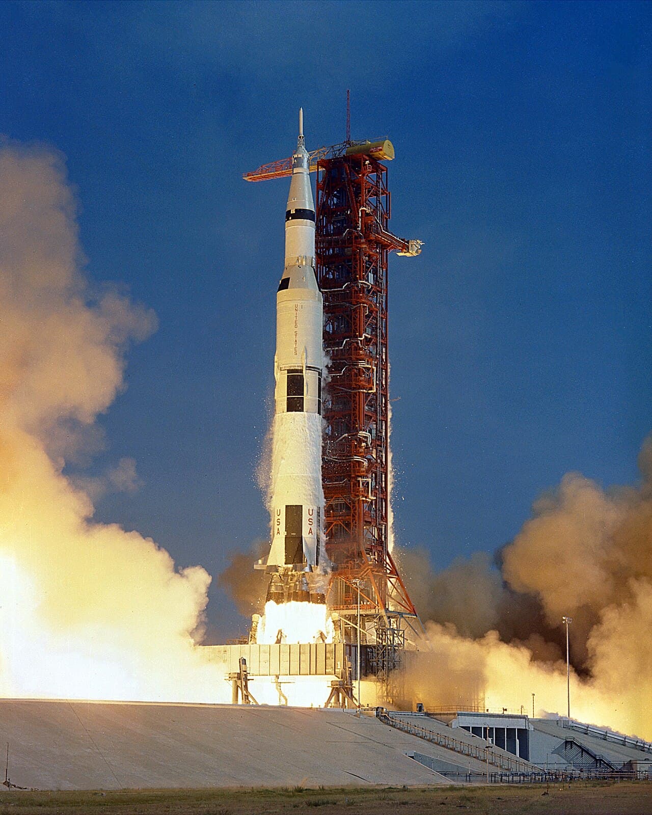 La fusée Saturn V au décollage d'Apollo 11, avec des flammes et de la fumée à sa base.