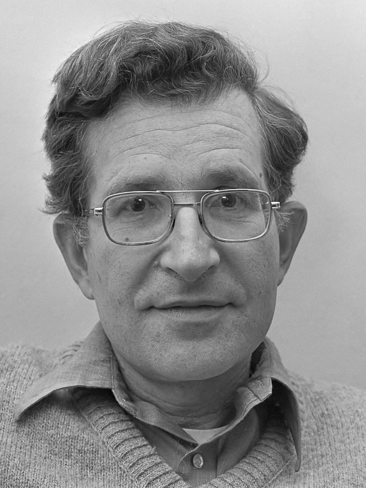 Photographie en noir et blanc du linguiste Noam Chomsky en 1977, portant des lunettes et un pull.