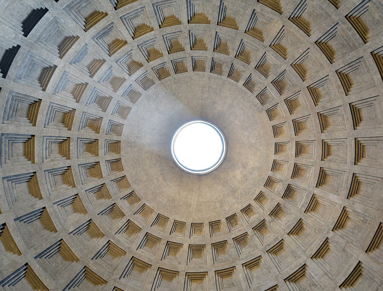 Le dôme à caissons en béton du Panthéon à Rome, vu d'en bas, avec une ouverture circulaire, l'oculus, en son centre laissant entrer la lumière.