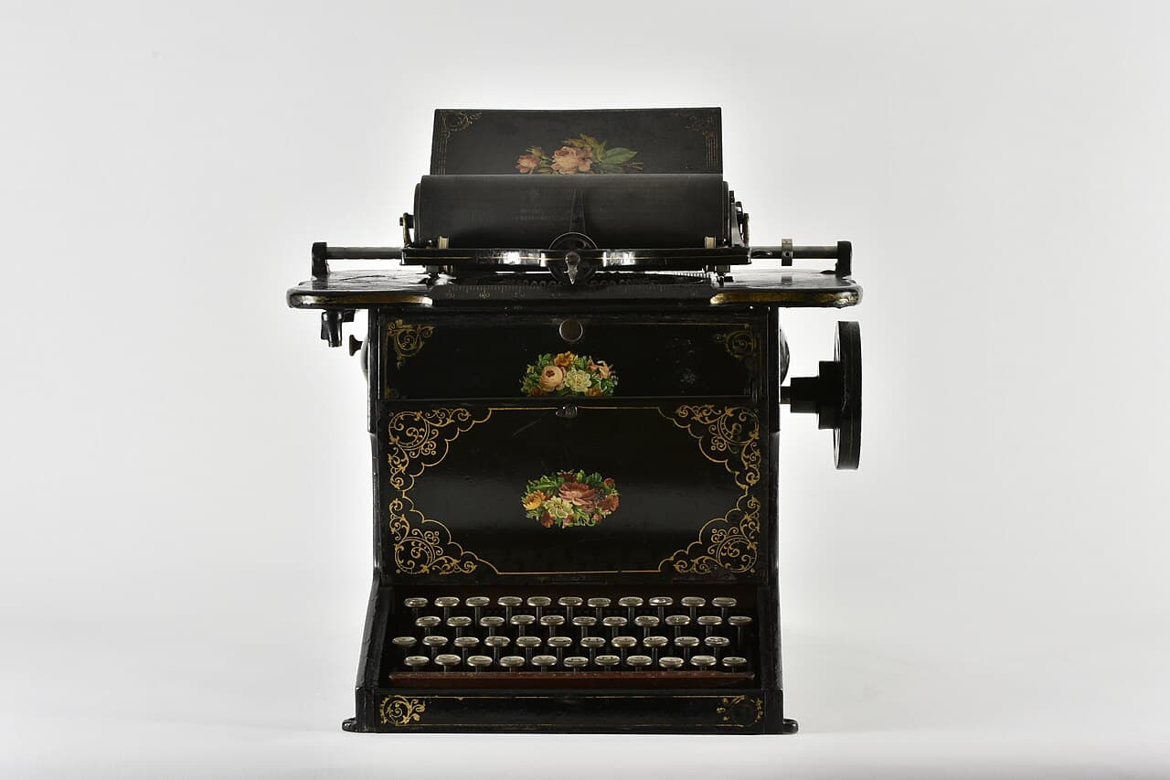 Une machine à écrire Sholes et Glidden noire et ornée de 1873, décorée de fleurs peintes, avec des touches rondes disposées sur quatre rangées.