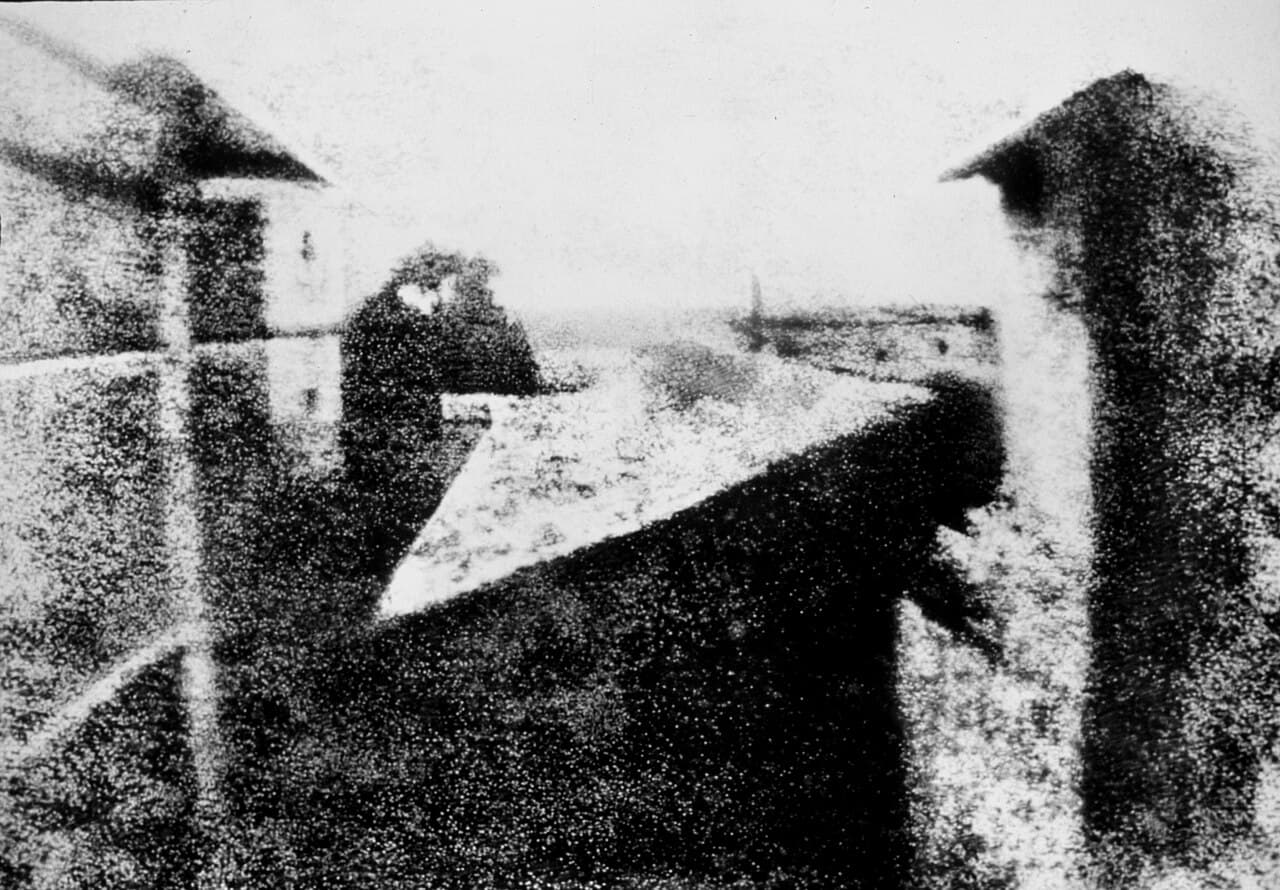 Une image floue, granuleuse et de teinte sépia de toits et d'une cour, à peine distincte, sur une plaque d'étain vieillie.