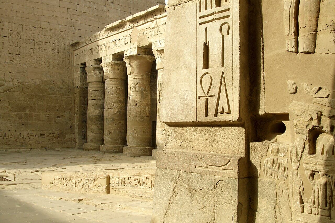 Rangées de hiéroglyphes égyptiens gravés et peints couvrant un mur de pierre au temple de Ramsès III à Médinet Habou.