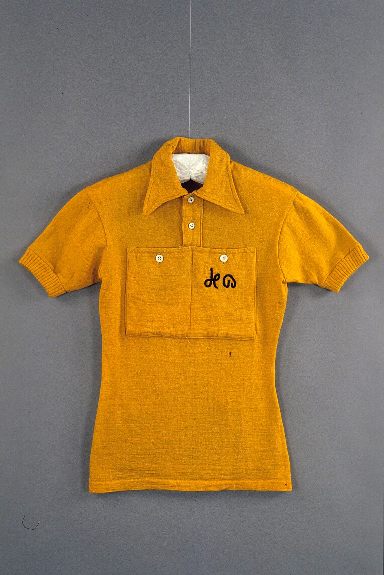 Un maillot de cyclisme jaune en laine du Tour de France 1954, porté par Louison Bobet, photographié à plat dans une collection de musée