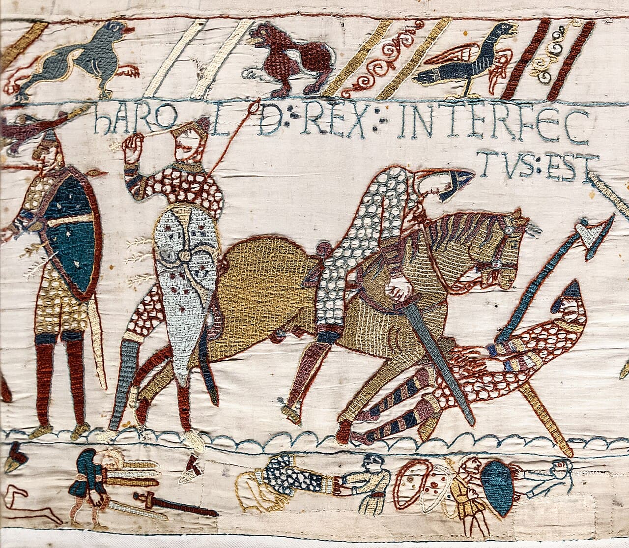 Scène brodée de la tapisserie de Bayeux montrant des chevaliers normands à cheval et des soldats anglais au combat, sous une inscription latine.