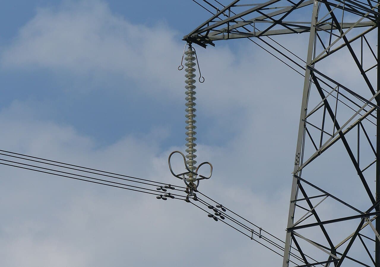 Gros plan sur des câbles à haute tension auxquels sont fixés de petits poids métalliques en forme d'haltère.